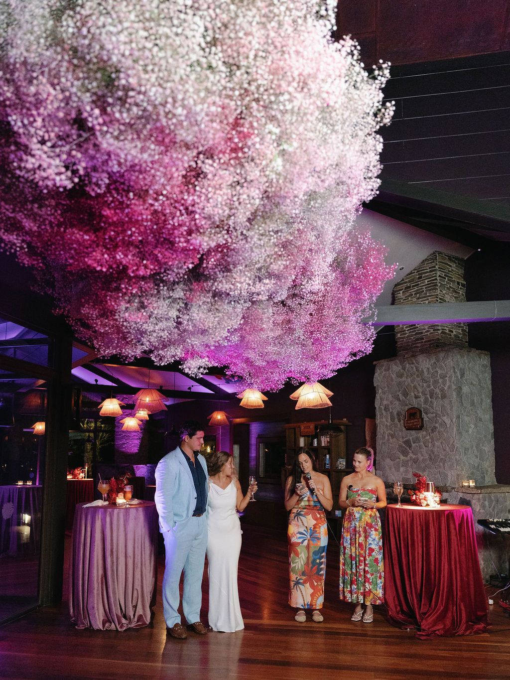 Guests gathered beneath a dramatic pink floral installation during a destination wedding welcome party
