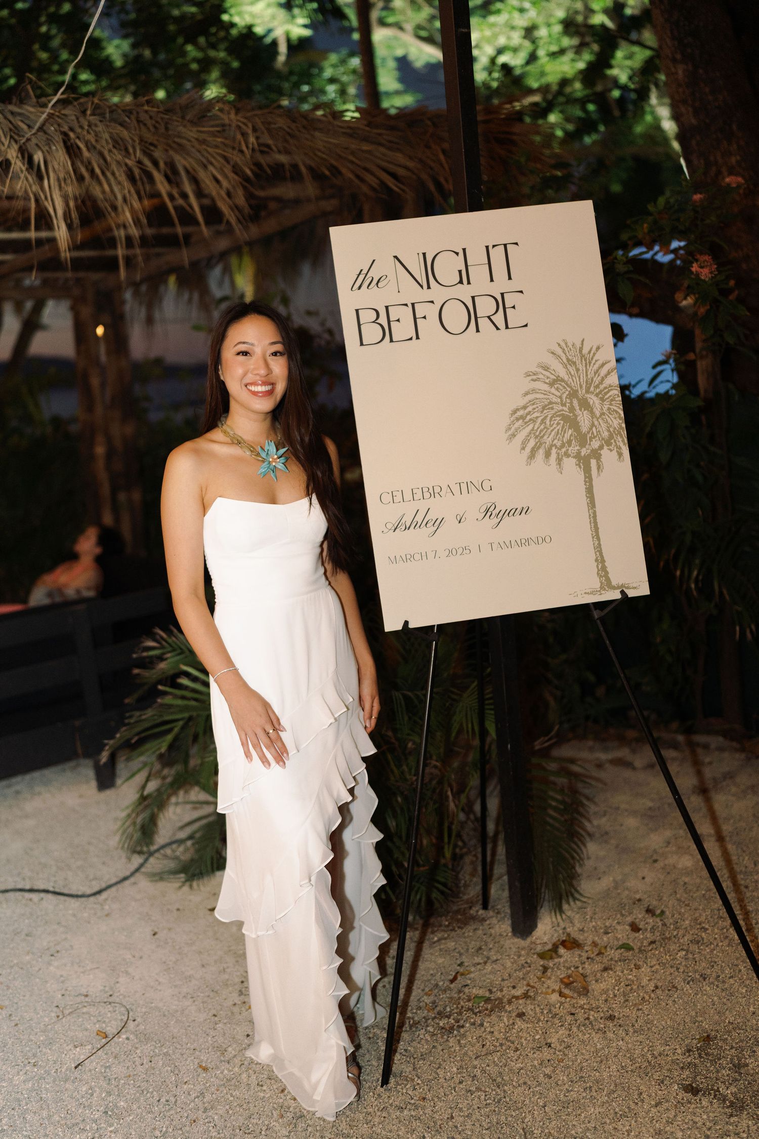 Ashley beside the welcome party sign for her wedding weekend with Ryan in Tamarindo, Costa Rica