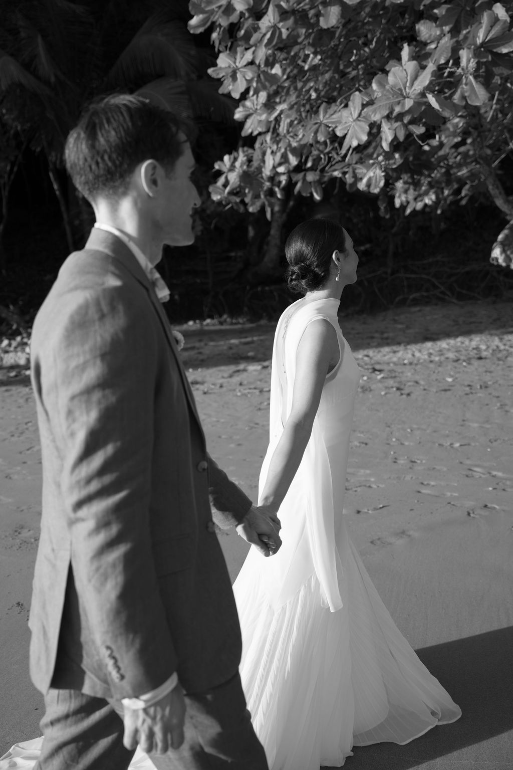 Black-and-white candid photograph of the couple walking along the beach in Manuel Antonio.