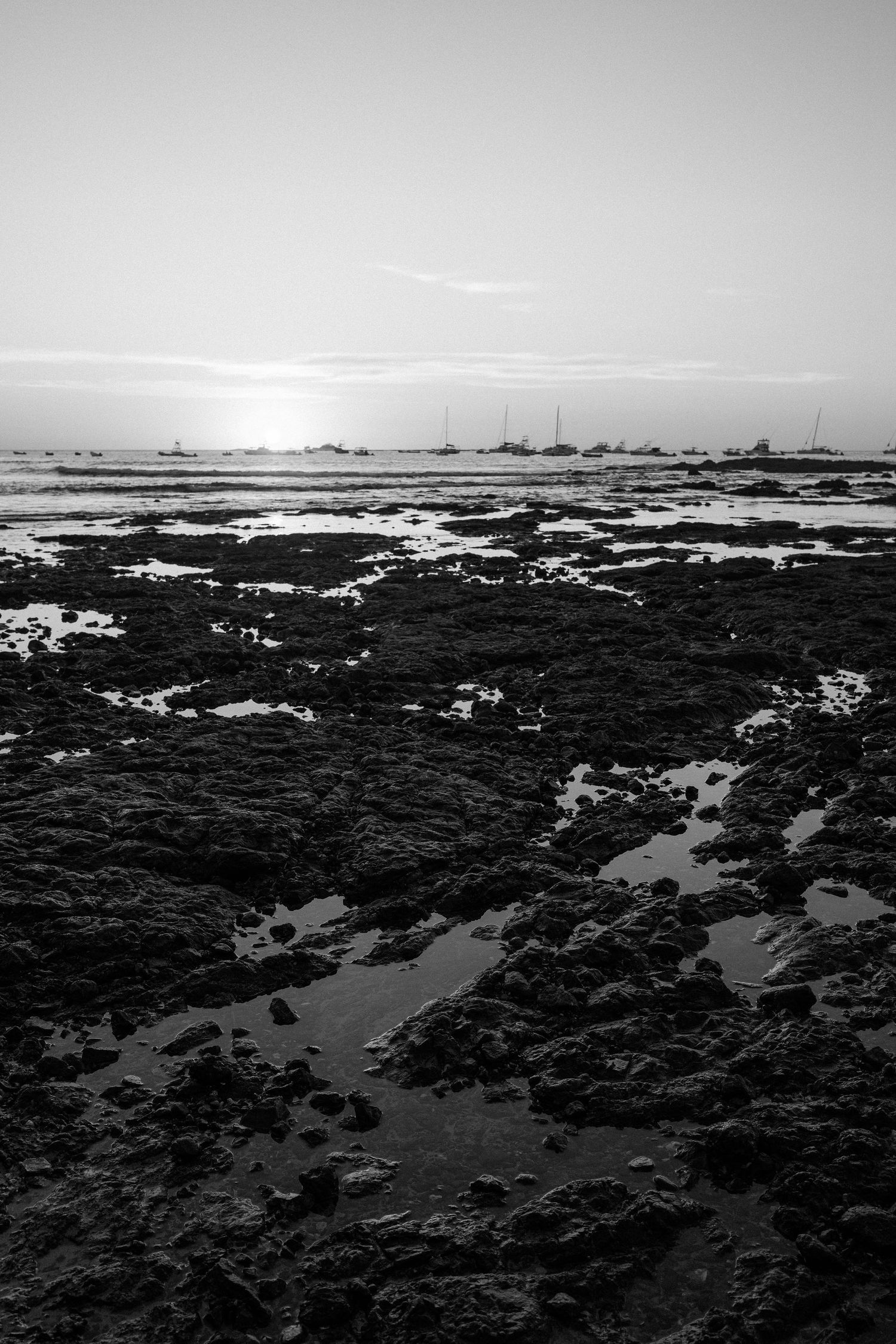 Rocky coastline and boats off Tamarindo, Costa Rica photographed in black and white