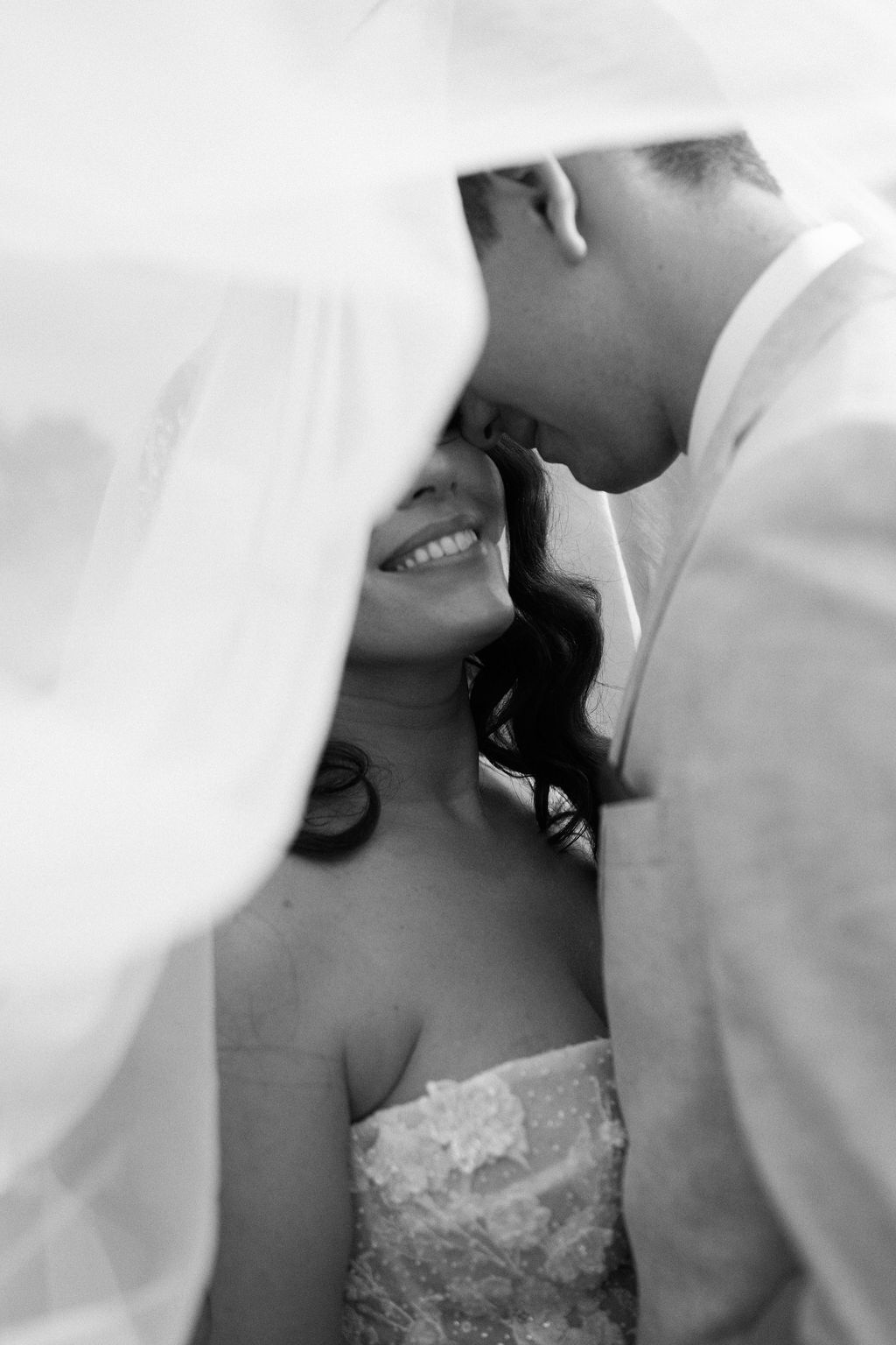 Intimate black and white portrait of a couple beneath the bride’s veil