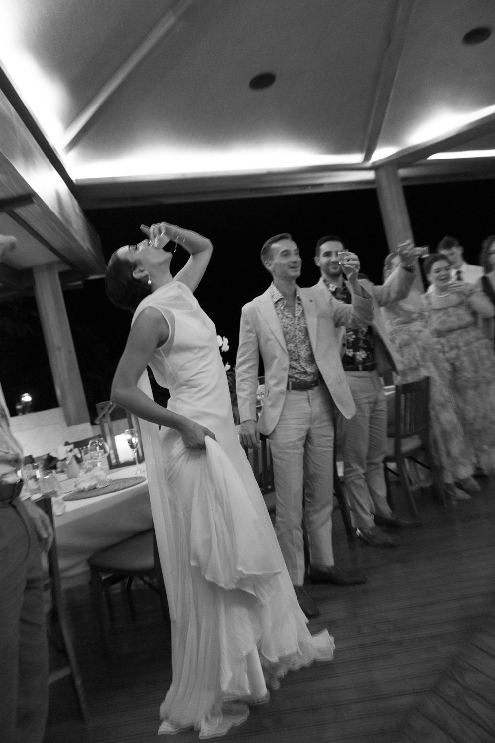 Black-and-white photograph of a bride and groom sharing drinks with guests at their Costa Rica wedding reception.
