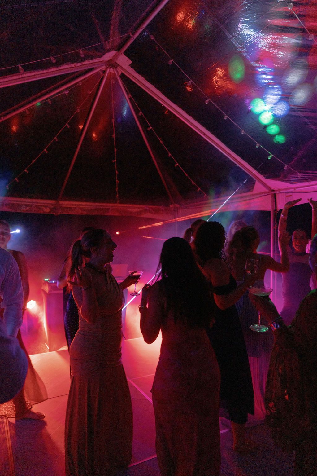 Wedding guests dancing under colorful lights during the Las Palapas reception