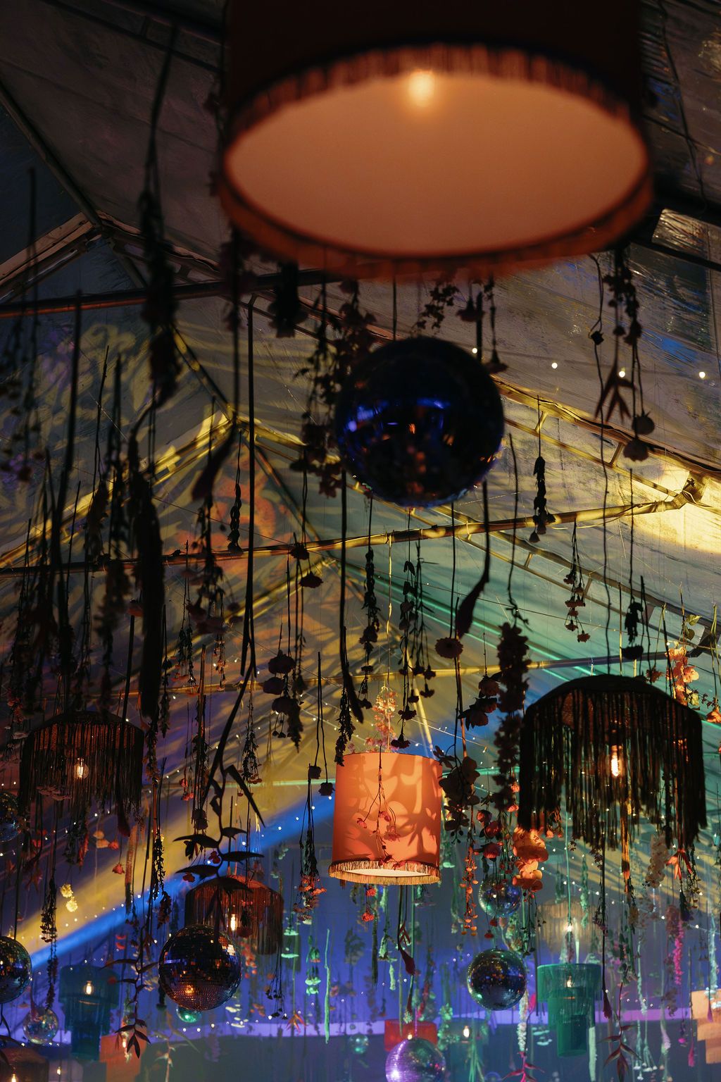 Wedding reception ceiling decorated with hanging flowers, lamps, and disco balls in Costa Rica