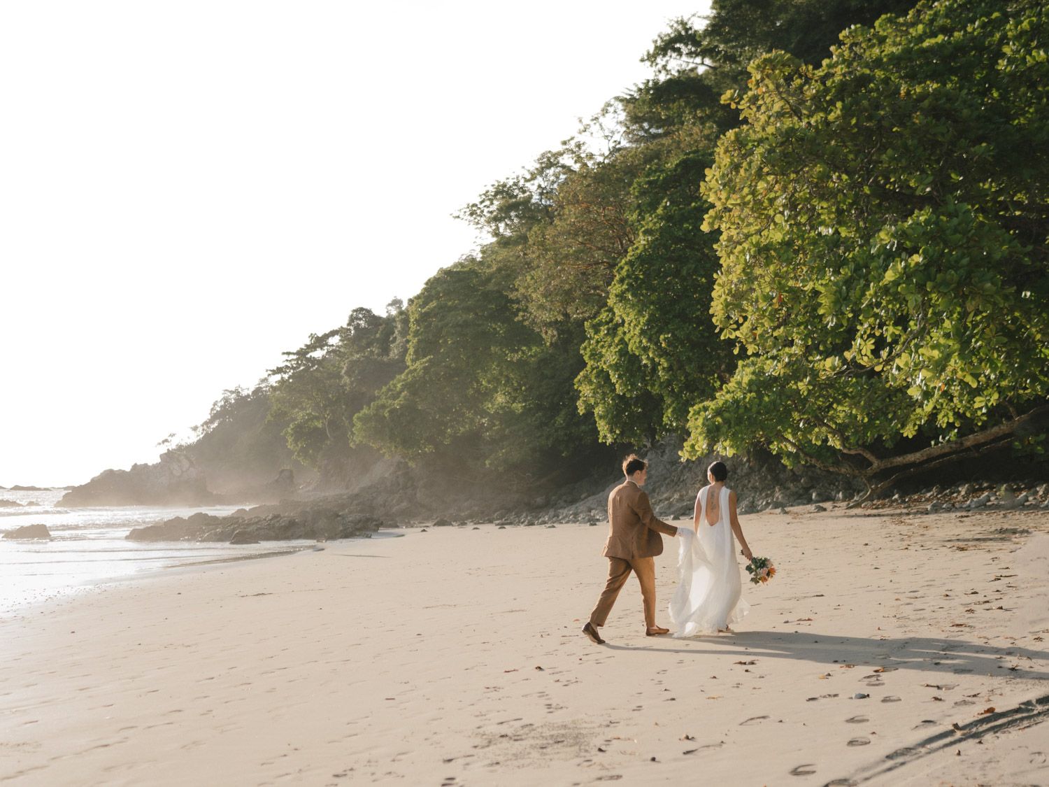 Bride and groom walking hand in hand along a tropical beach in Manuel Antonio Costa Rica