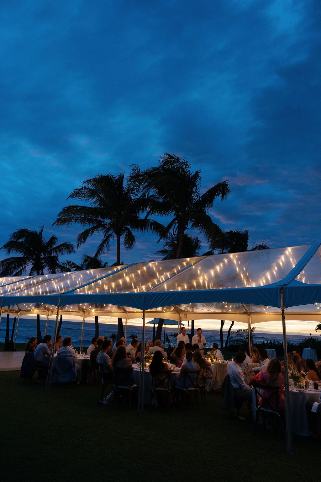 Outdoor wedding reception beneath a clear tent at blue hour at Las Palapas