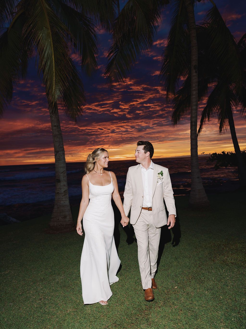 Morgan and Britton walking beneath palm trees during a dramatic Pacific sunse