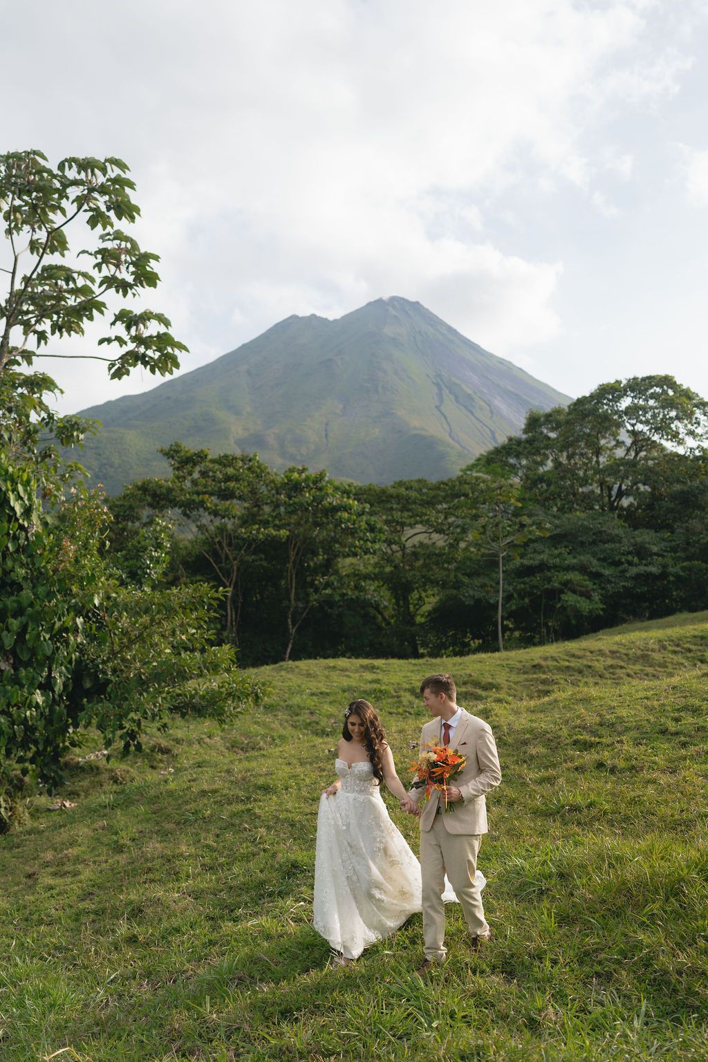 Newlyweds walking together with Arenal Volcano overlooking La Fortuna