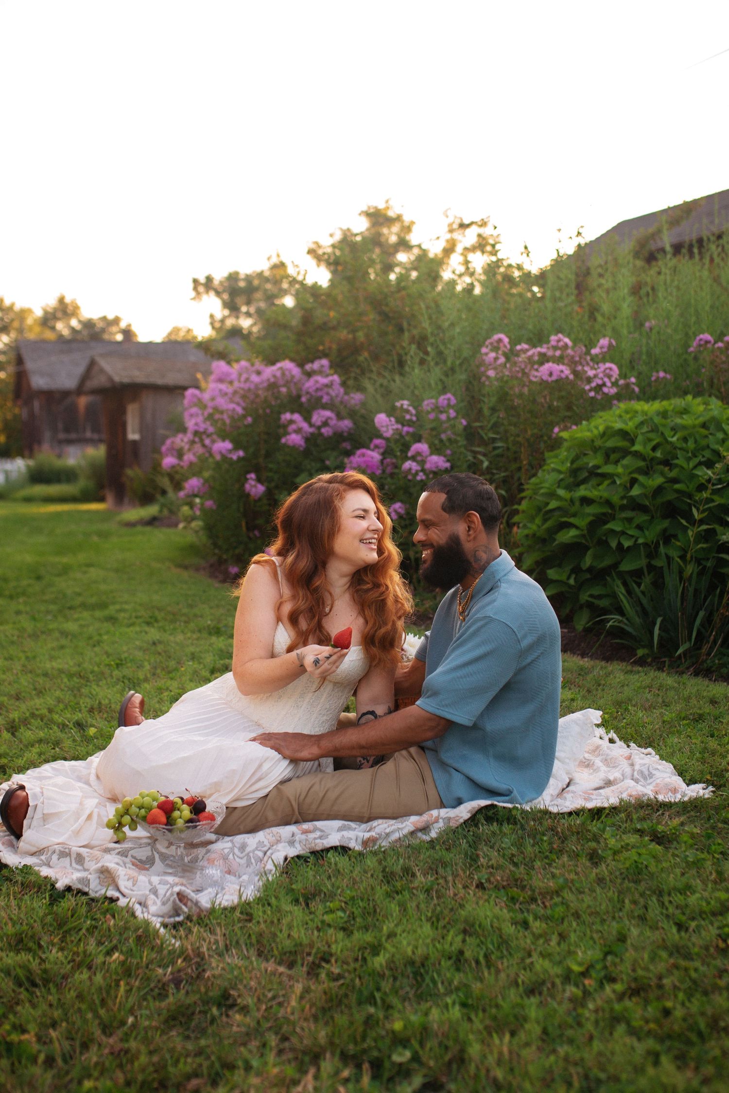 Happy interracial couple enjoying a romantic picnic at sunset surrounded by blooming flowers.