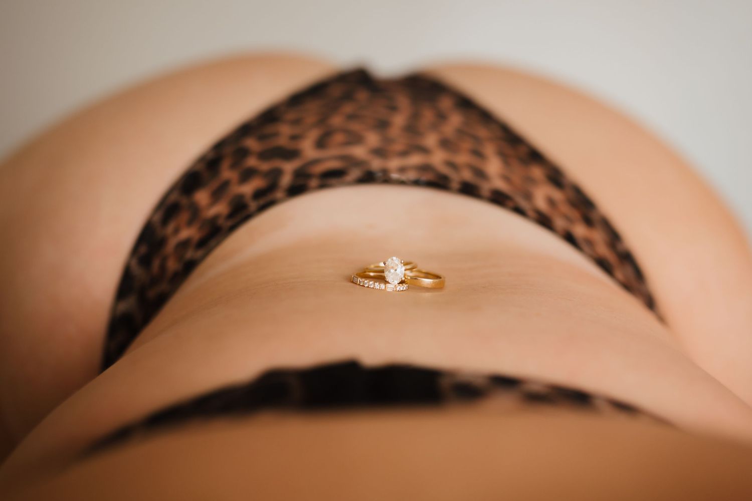 Close-up of leopard print underwear with gold diamond ring on lower back.
