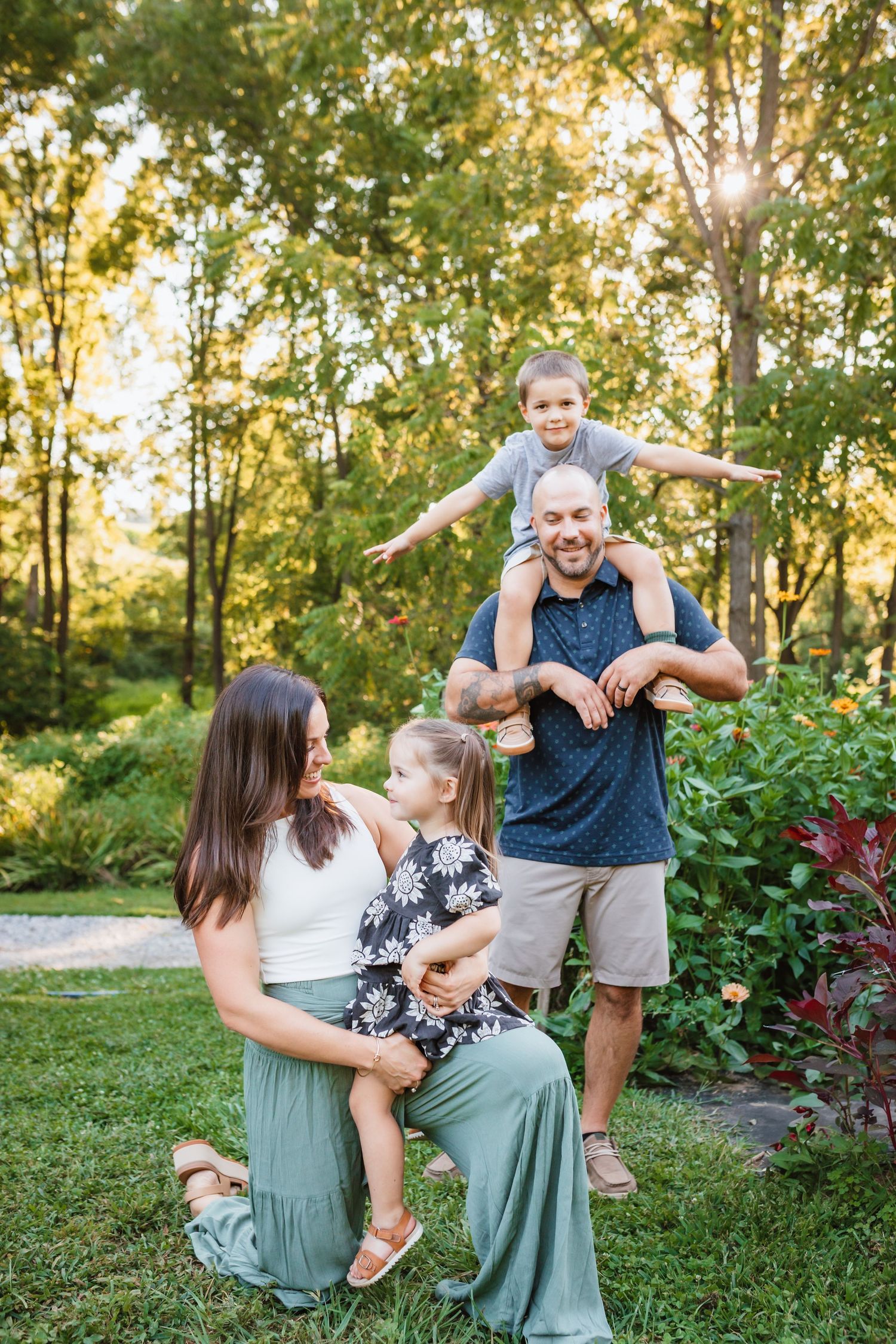 Happy family of four enjoying outdoor portraits in a lush green garden at golden hour.