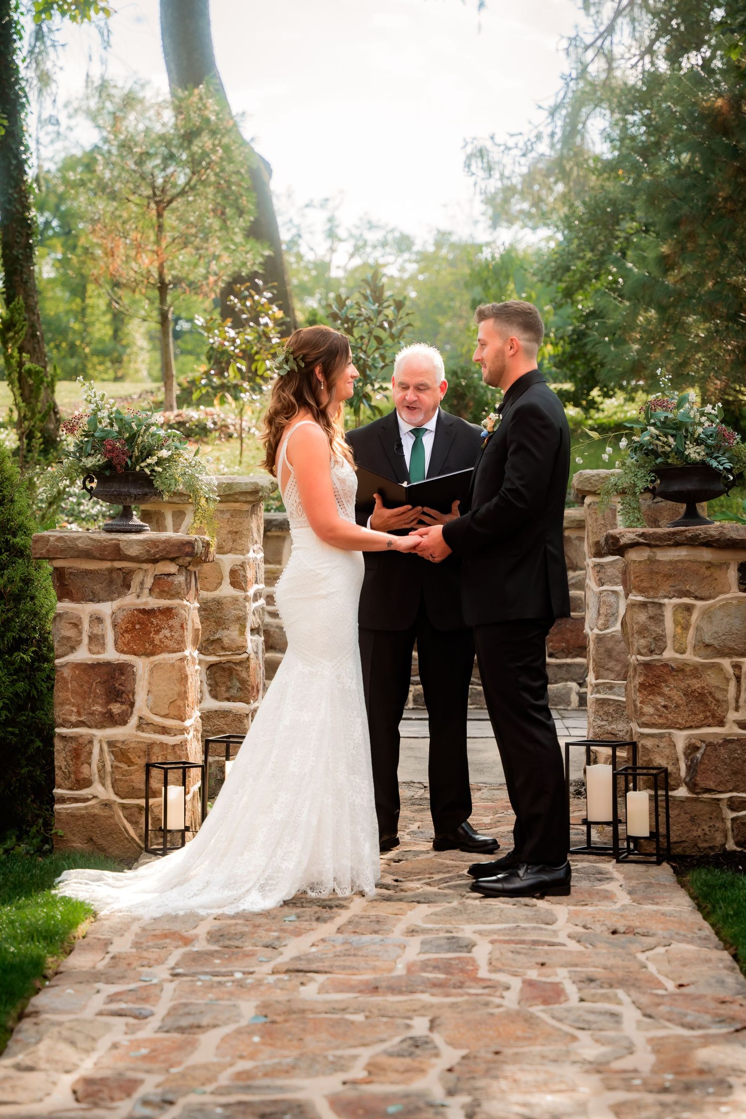 Bride and groom exchanging vows at outdoor stone ceremony altar with officiant.
