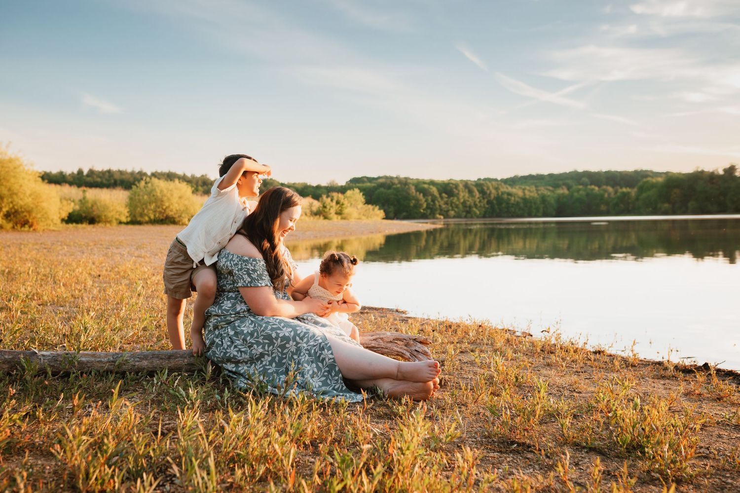 Family relaxing by a serene lake at golden hour, enjoying a beautiful sunset together.