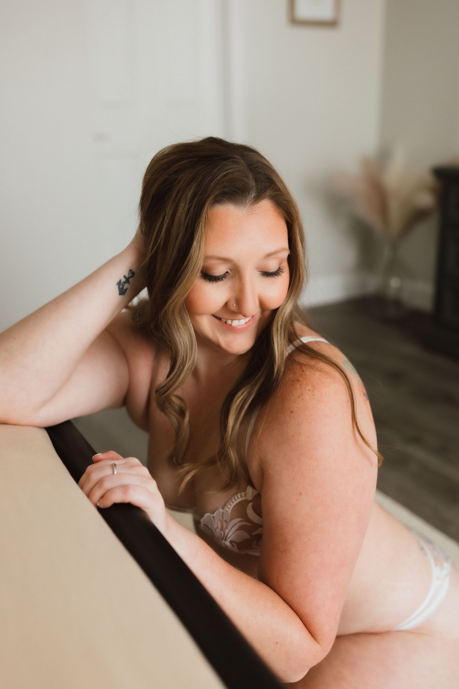 Smiling woman in sheer lingerie leaning over black metal bed frame.