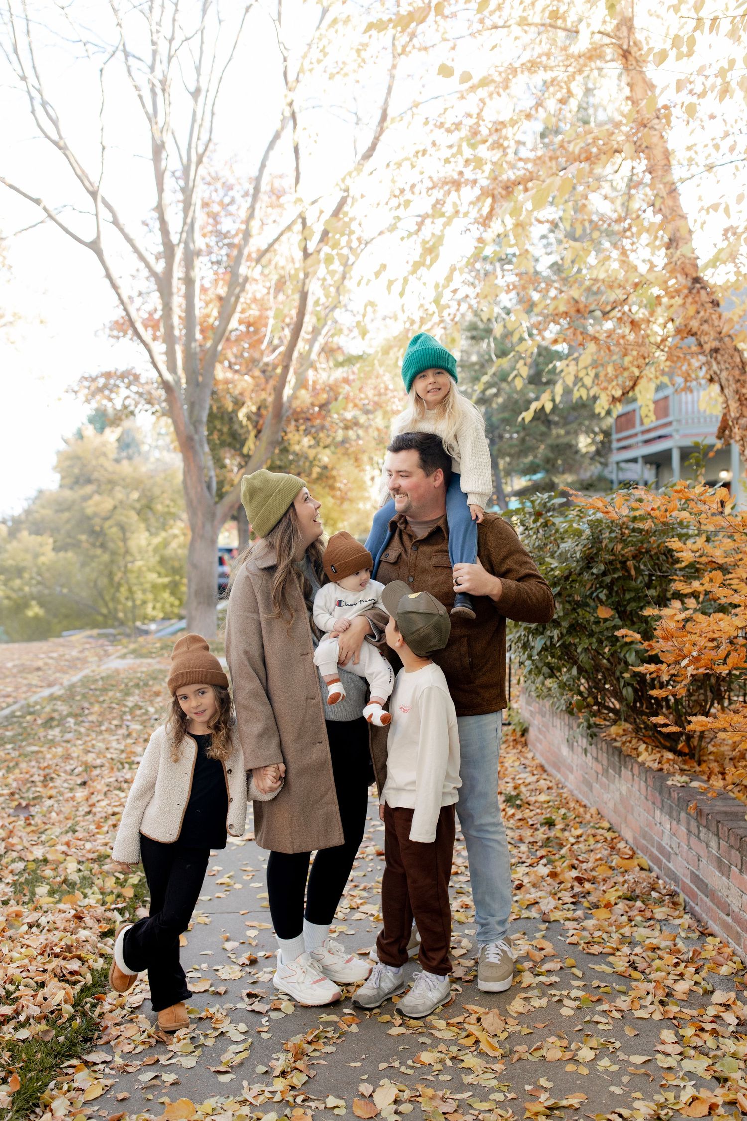 Family of five enjoying an autumn walk outdoors, with colorful fall foliage and warm seasonal clothing.