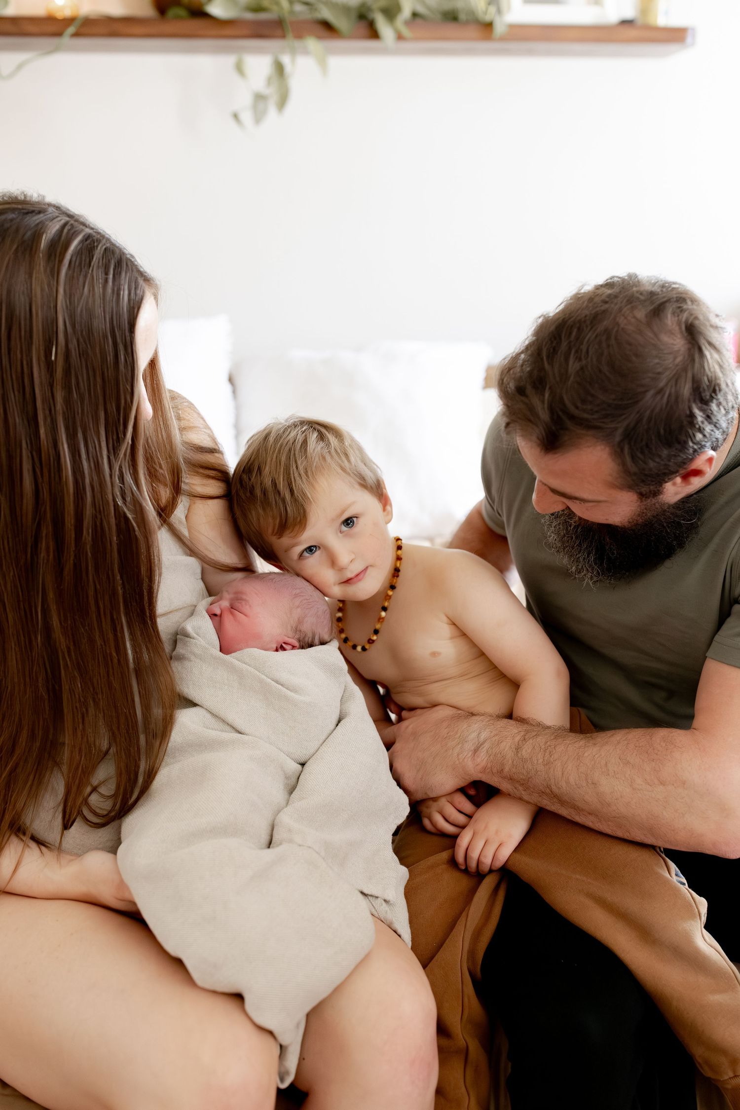 A series of intimate family moments showing parents cuddling and embracing their young child on a light-colored couch.