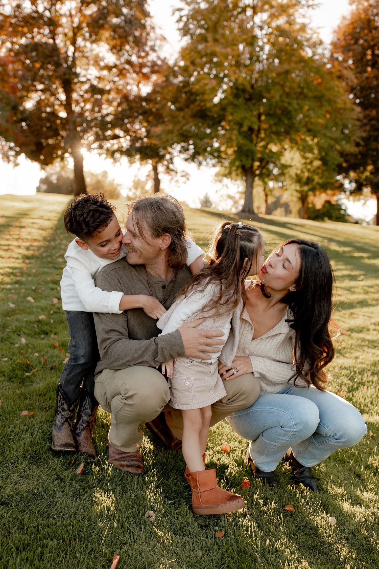 Family sharing playful moments together on grassy hill during golden hour sunset in autumn.