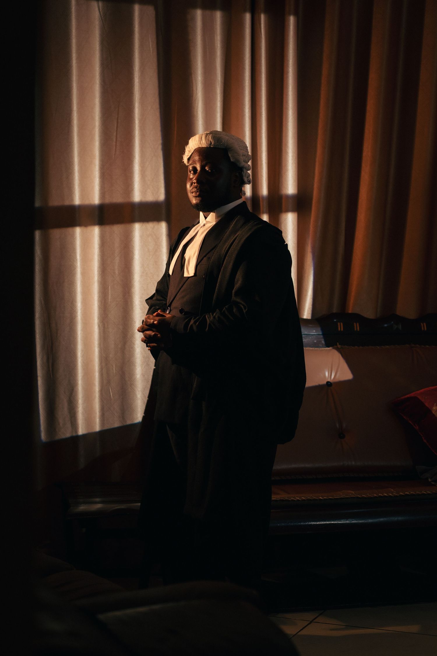 A man is dressed in a lawyer attire and is standing in a dark room