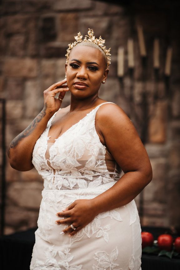 A stunning bride in a lace gown and delicate crown poses elegantly.