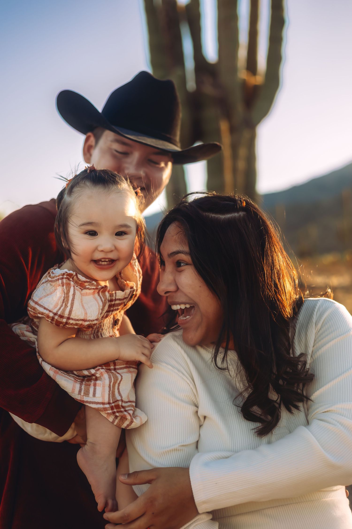 A family shares joyful laughter together in front of a desert landscape with saguaro cactus.