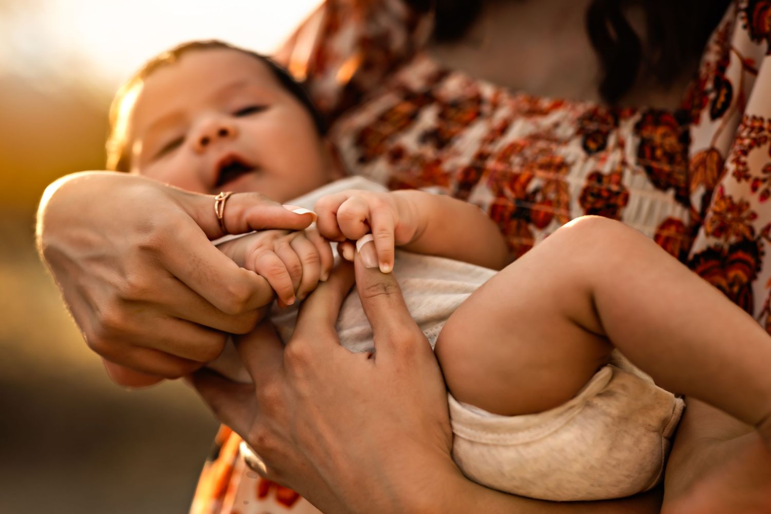 Close-up of gentle hands holding and caring for a small baby.