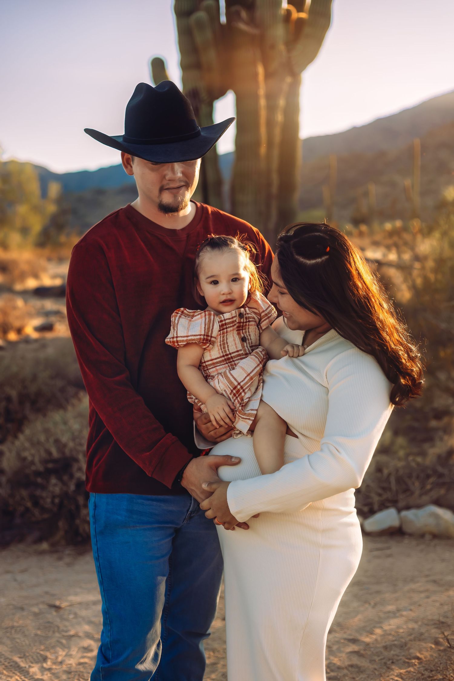 A desert family portrait with warm sunset lighting and saguaro cactus in the background.
