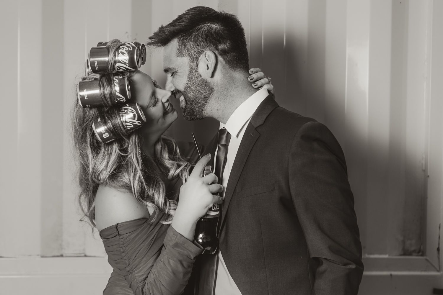 A romantic black and white photo of a couple in formal attire sharing an intimate moment while standing close together.