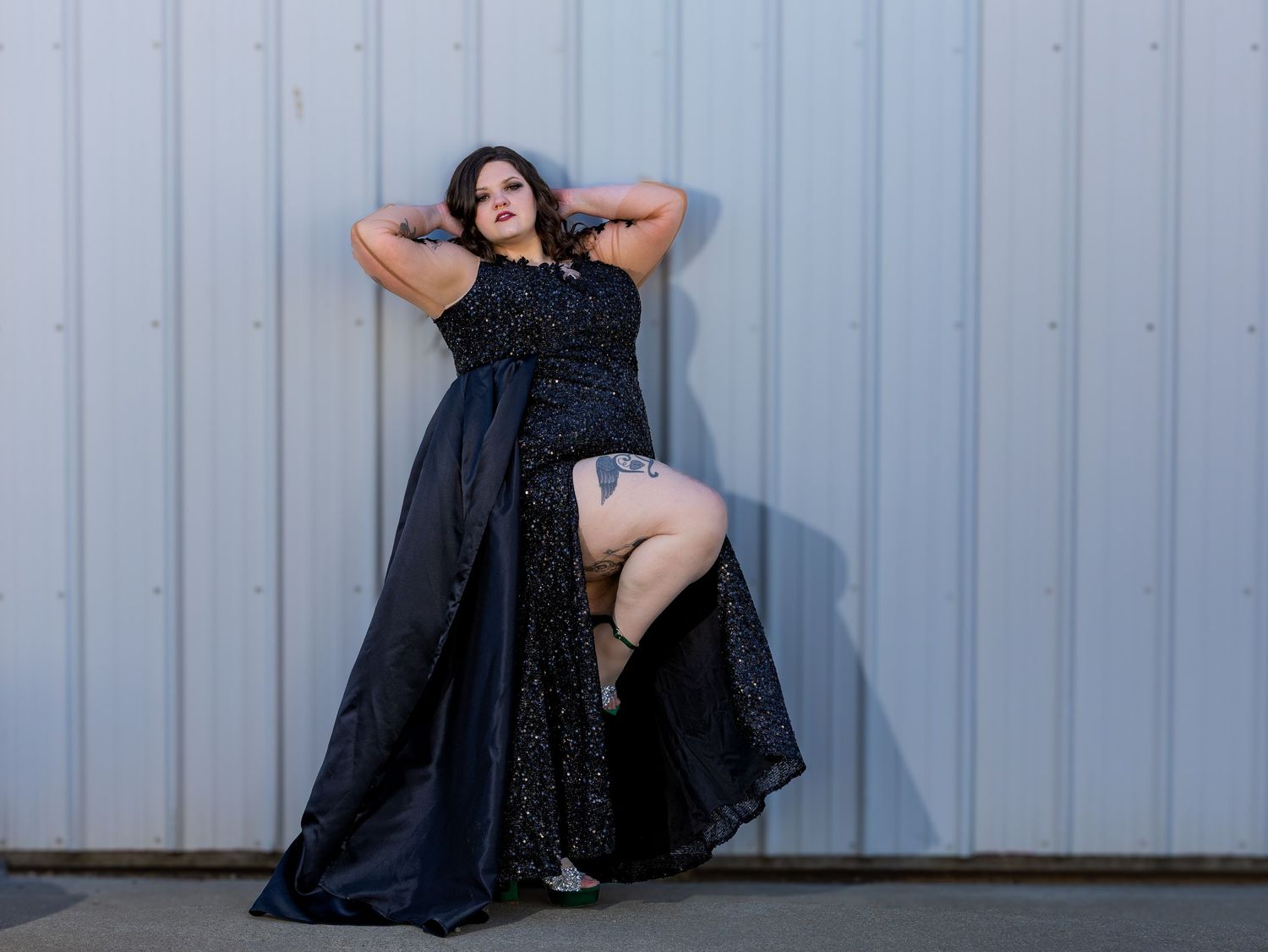 People in black evening attire pose expressively against a white corrugated wall for a photo session.