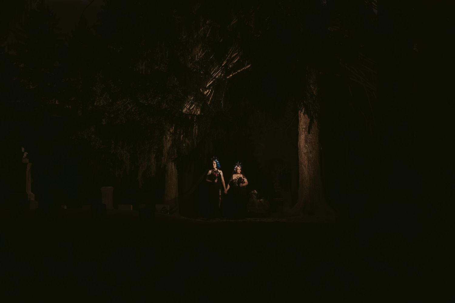 Two riders on horseback silhouetted against a dark forest backdrop illuminated by soft atmospheric lighting.