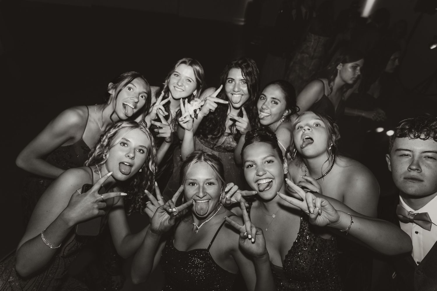 A black and white photo of people gesturing peace signs while celebrating at a party.