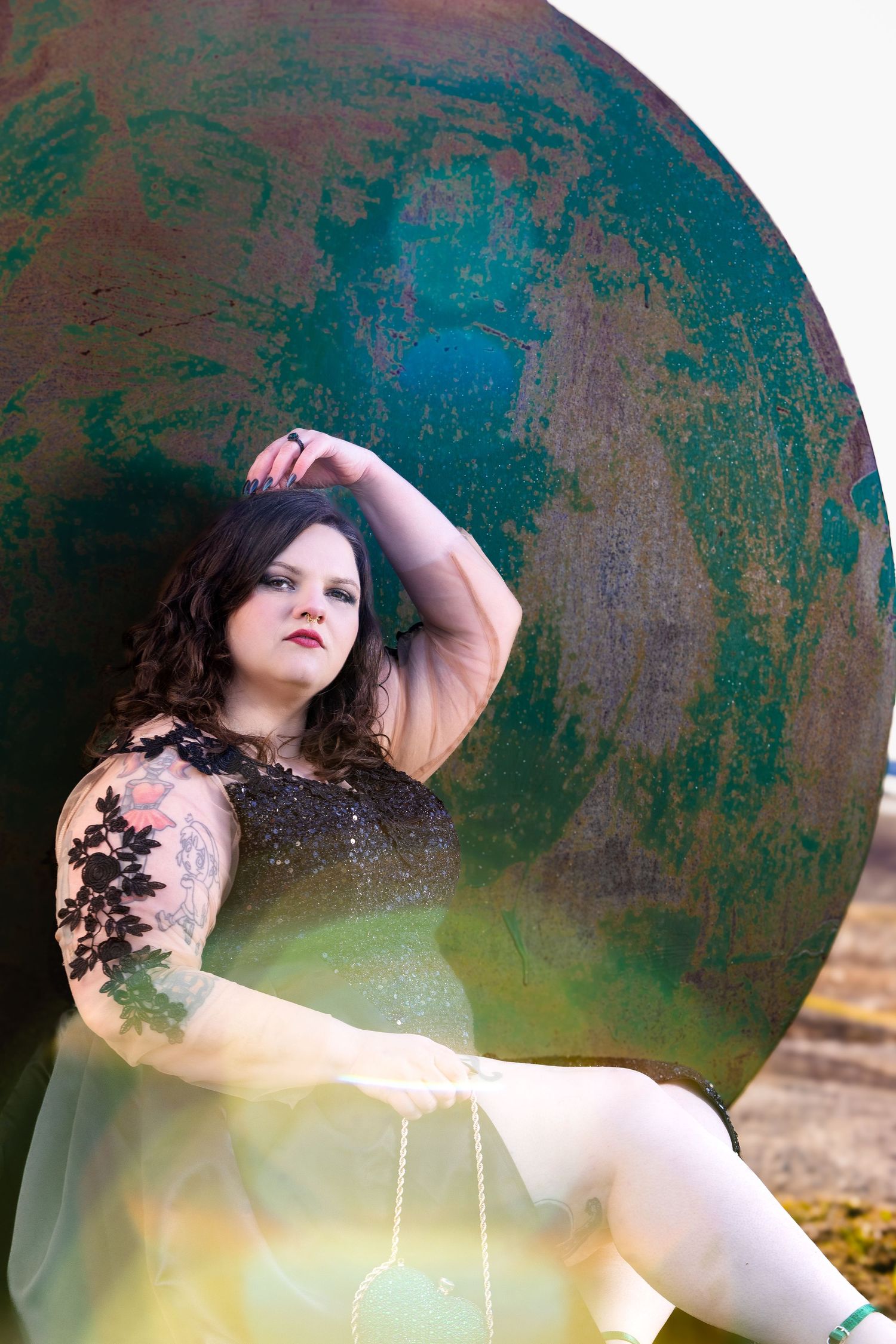 A fashion portrait against a teal textured backdrop featuring a sparkly dress and dramatic pose.