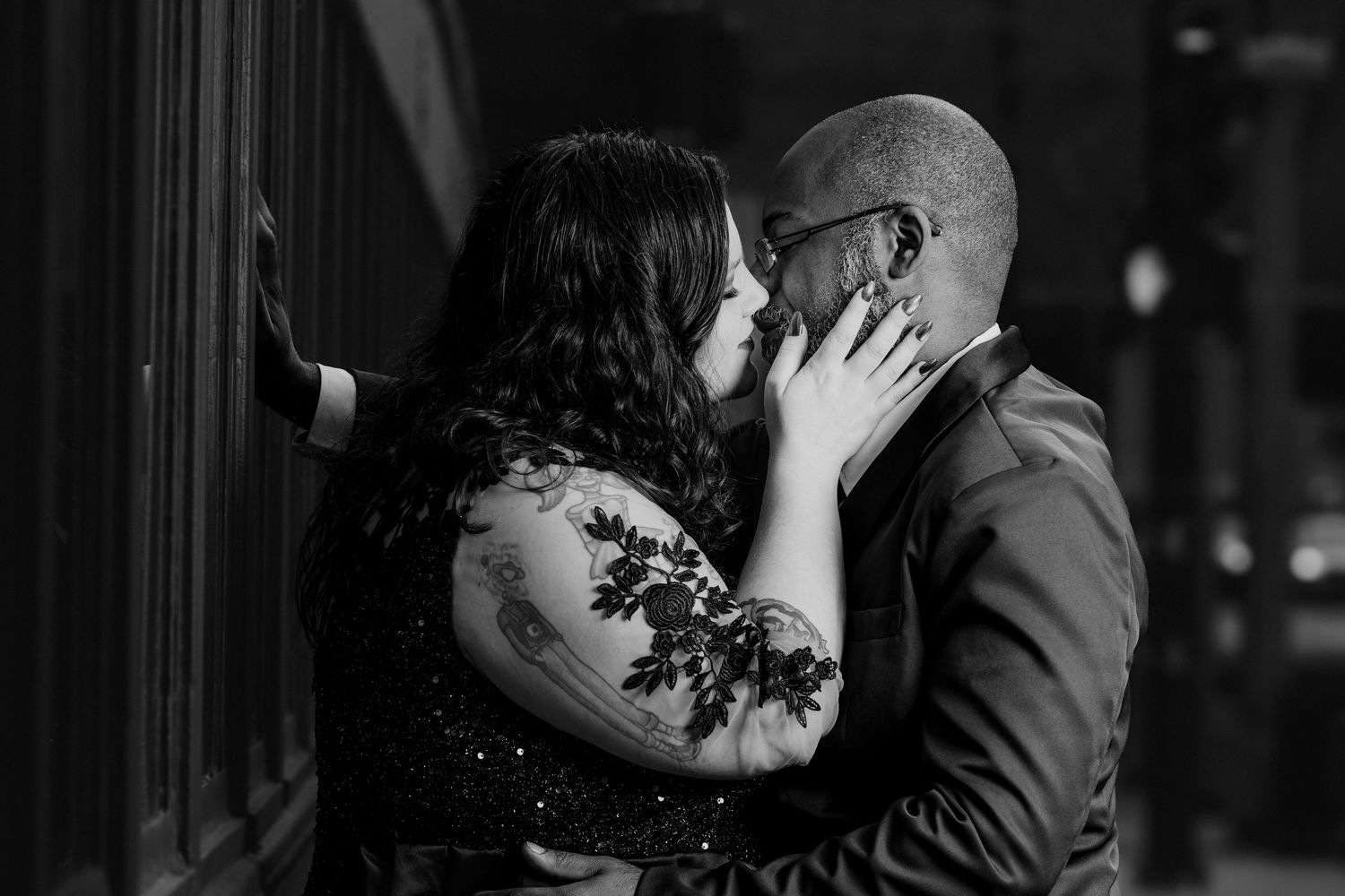 A romantic black and white photo captures an intimate moment between a couple sharing a loving kiss.
