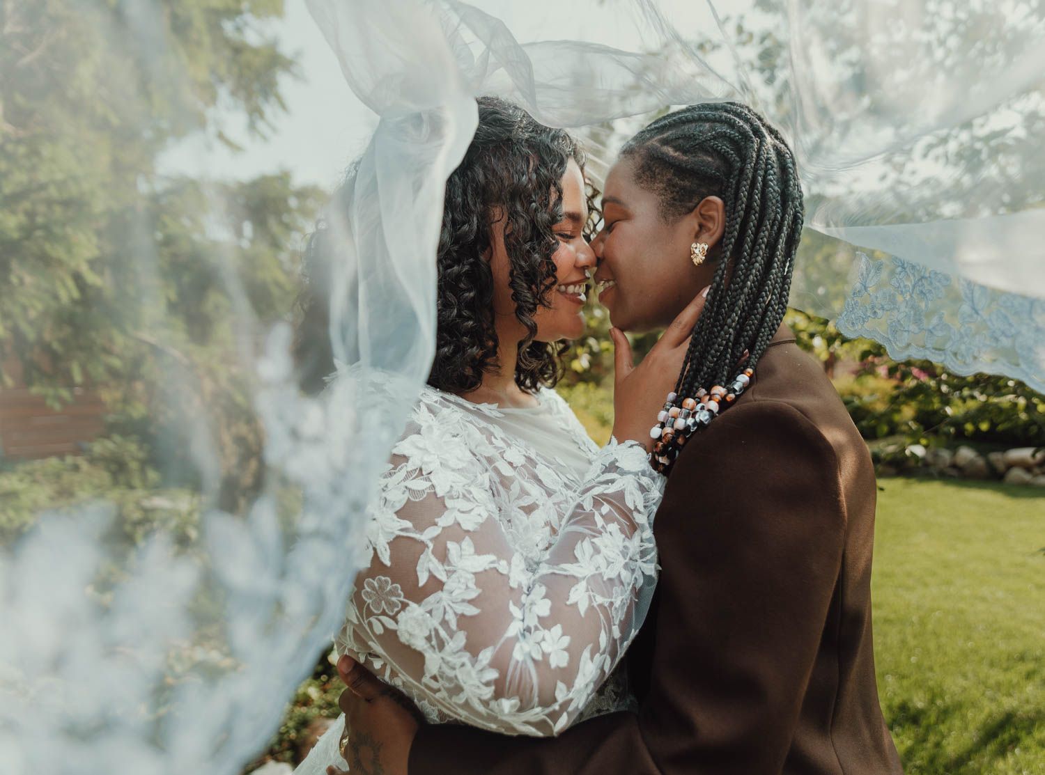 Romantic couple sharing a tender moment in a lace dress and dark clothing on a misty mountainside meadow.