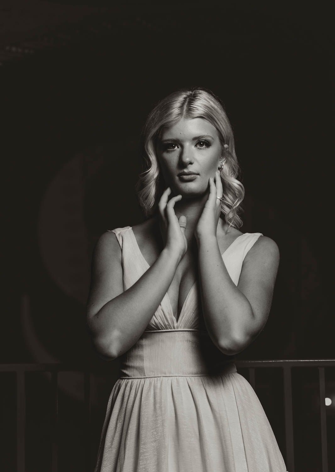 Black and white artistic boudoir photos show a woman in light dress posing against dark backdrop.