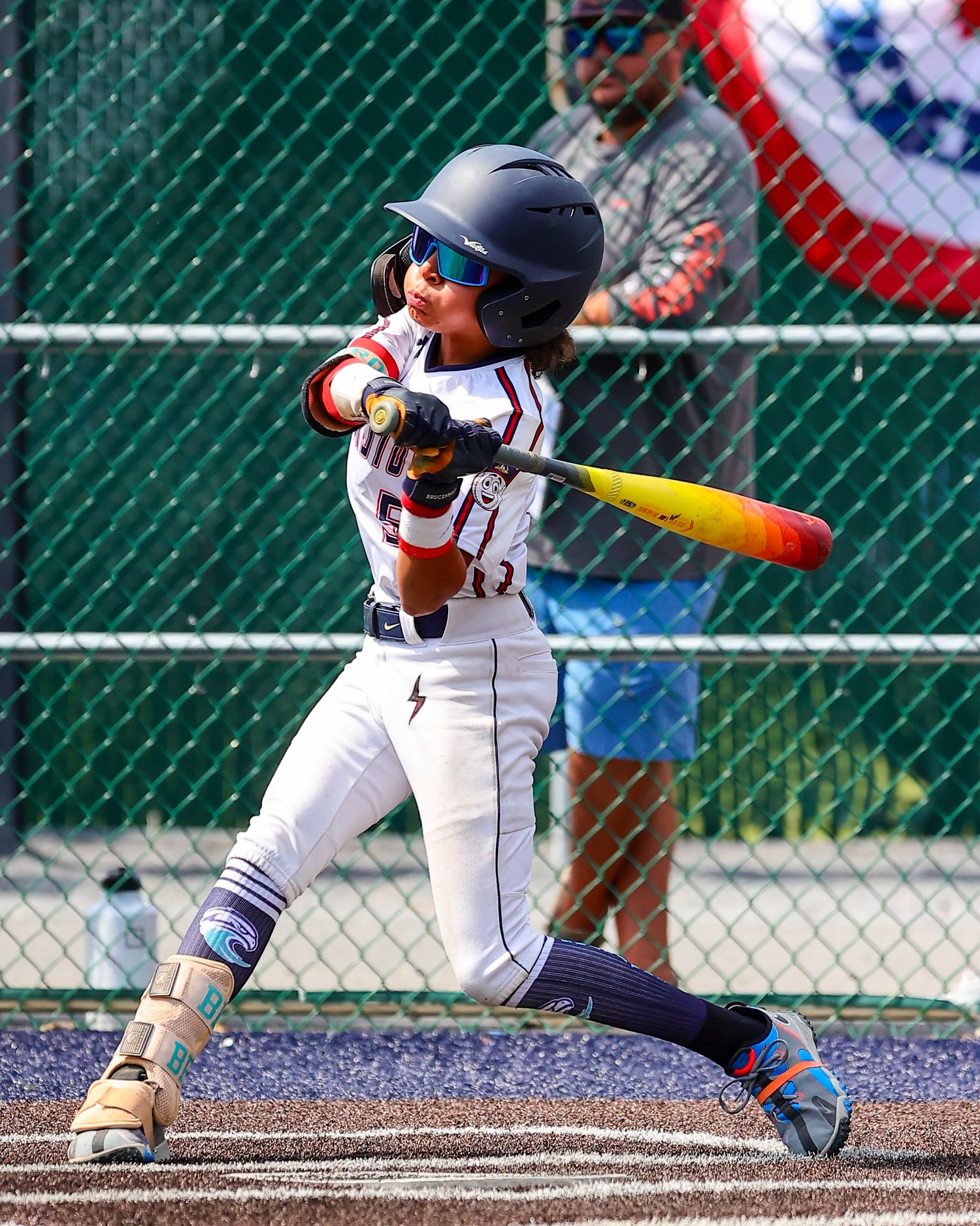 Baseball player in white uniform crouches in batting stance at home plate during game.