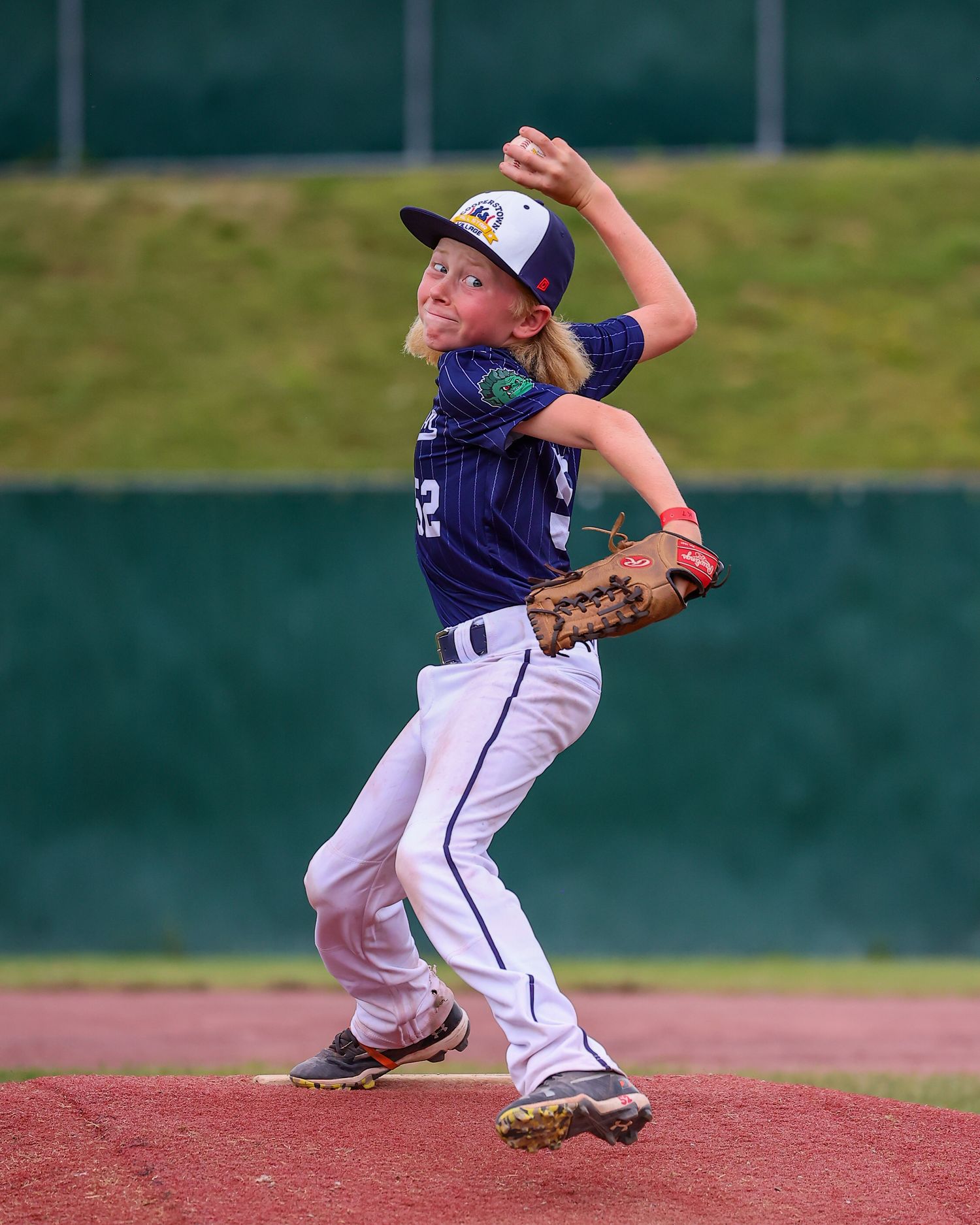 Baseball pitcher in navy uniform shown in sequence of motions delivering pitch from mound during game.