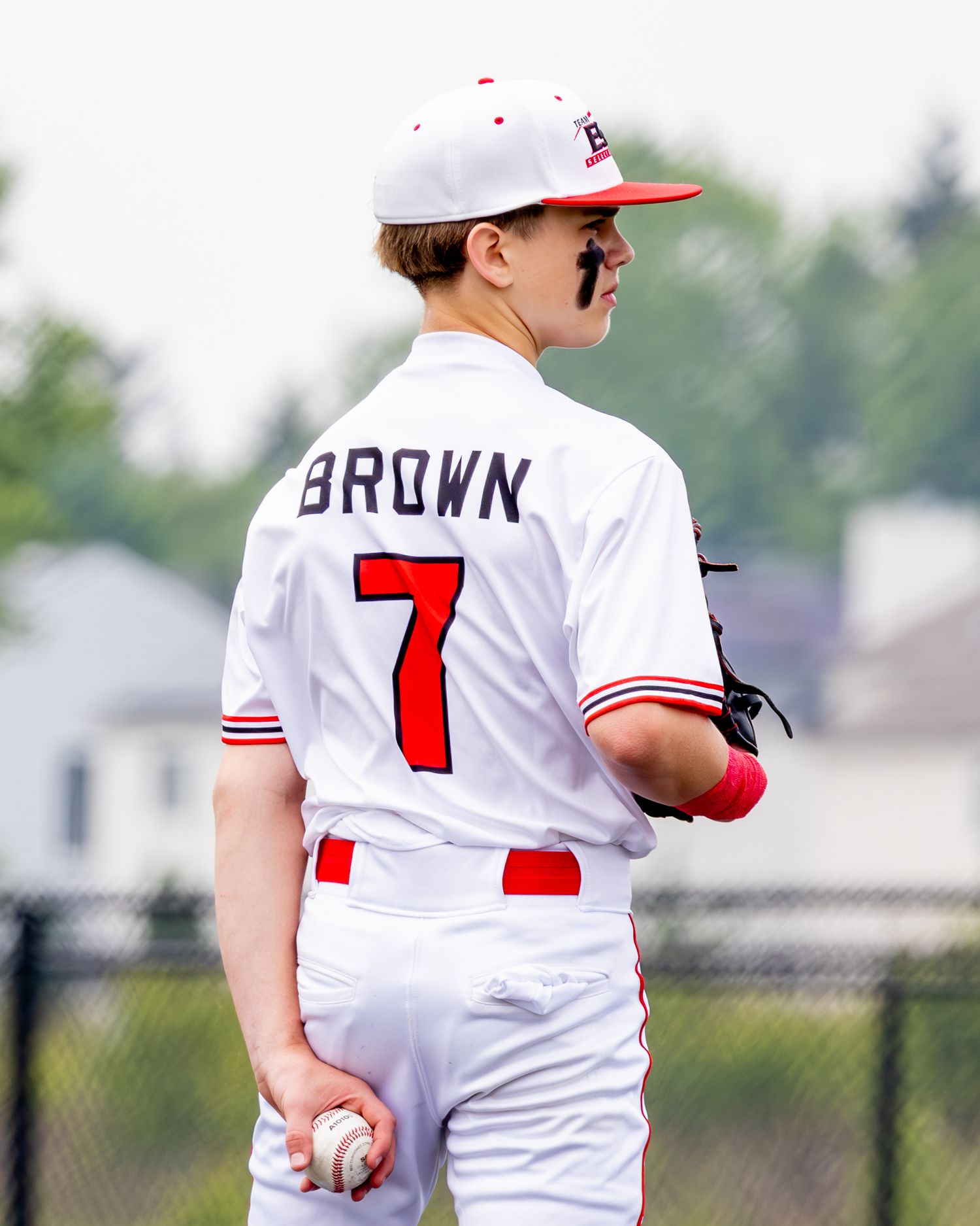 Baseball players in white and red uniforms stand on the field during a game.