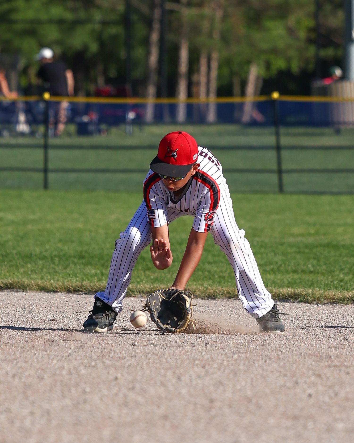 Baseball players practicing fielding drills on a dirt infield.