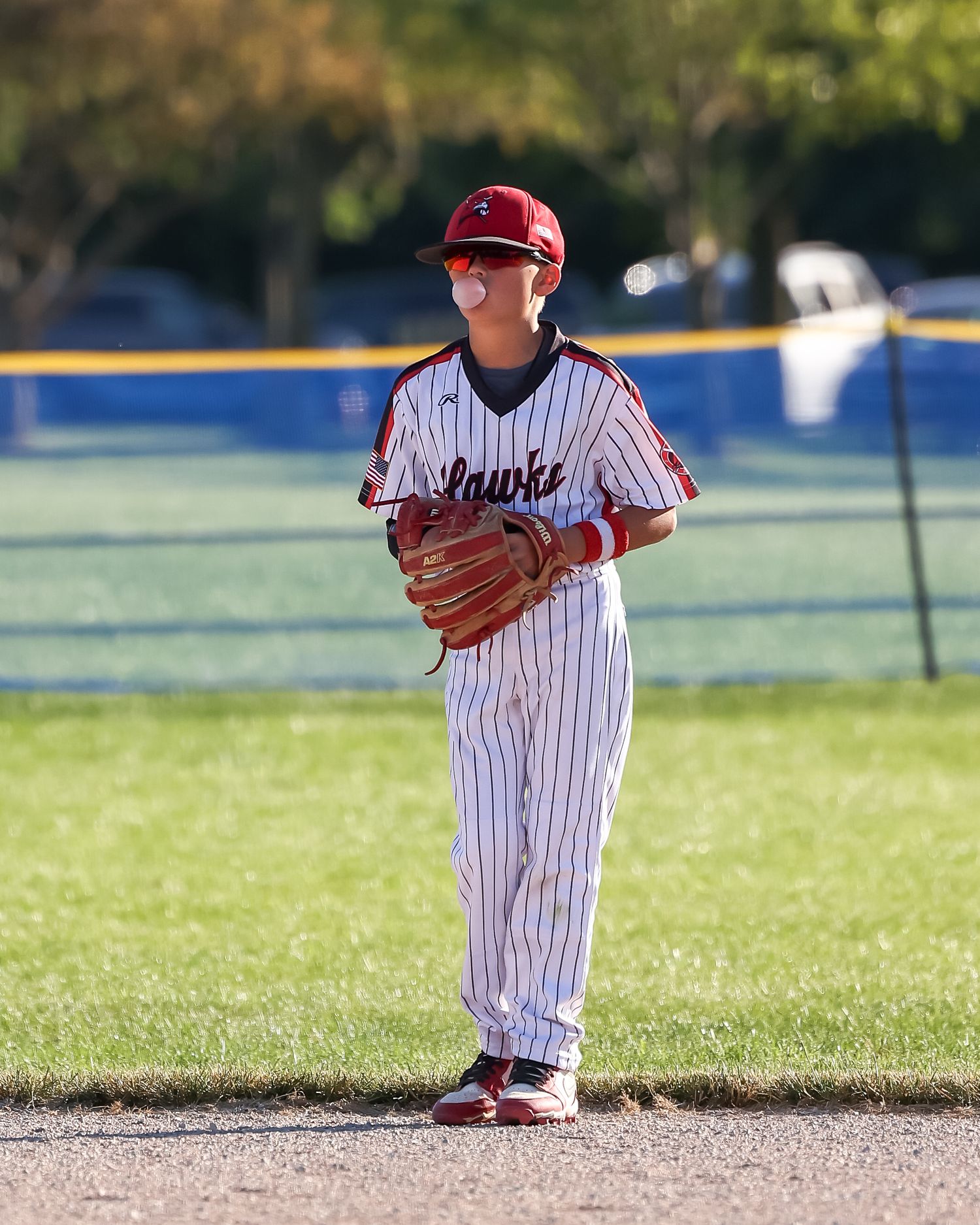 Baseball player in pinstripe uniform stands ready in fielding position on sunny day.