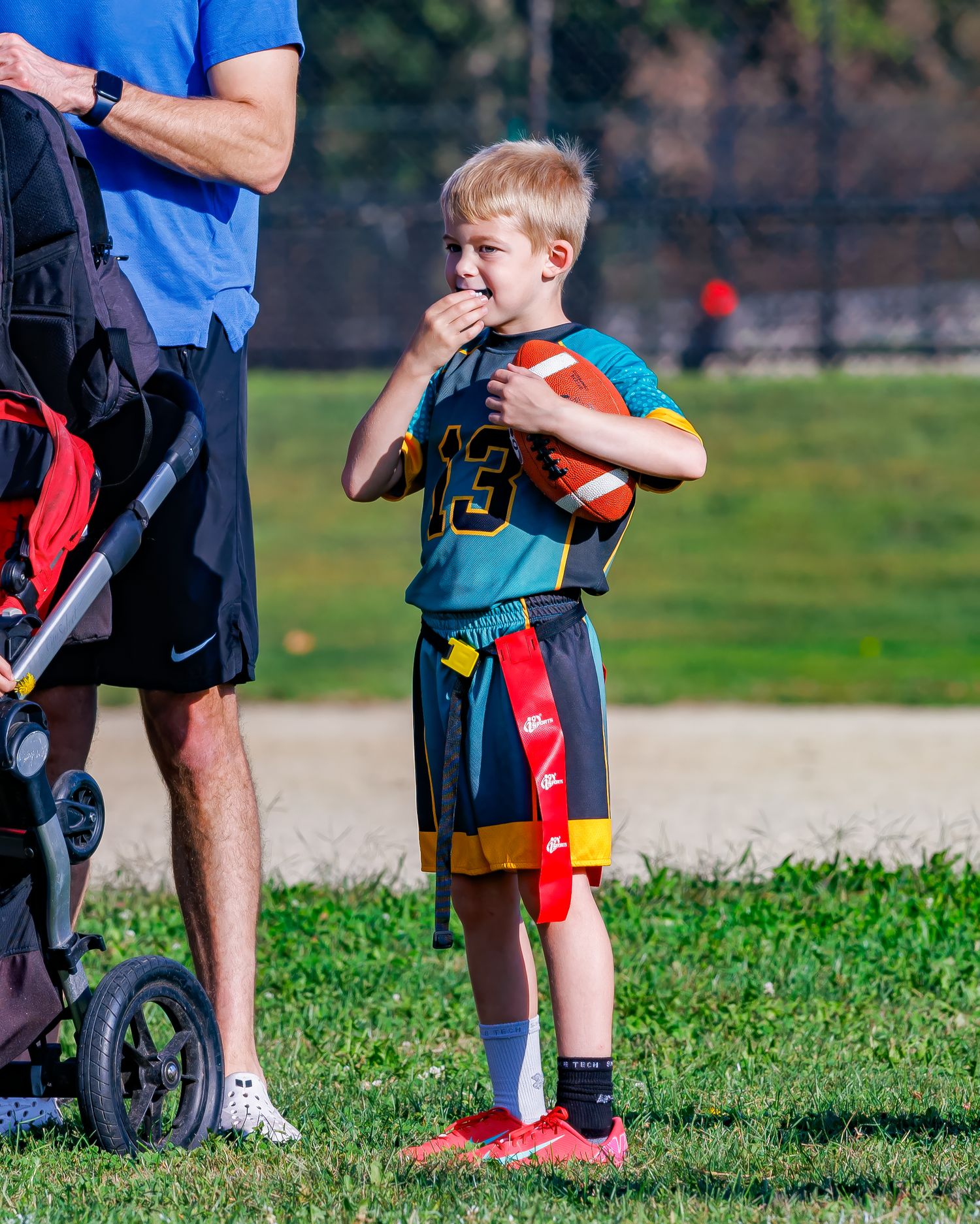 Young athletes in sports uniforms gather on a grassy field during a youth sports practice session.