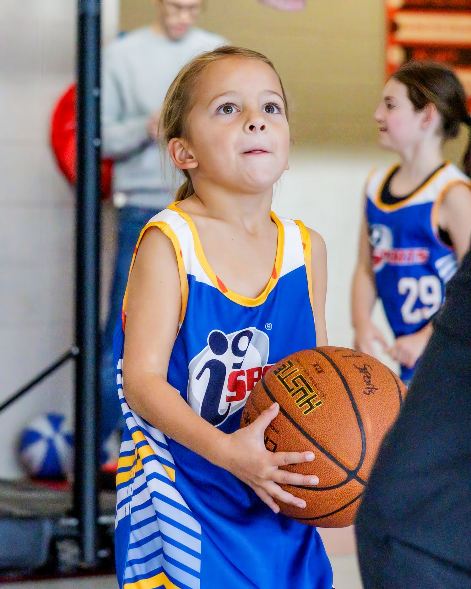 Young basketball player in a blue and white 76ers style jersey prepares to shoot during practice.