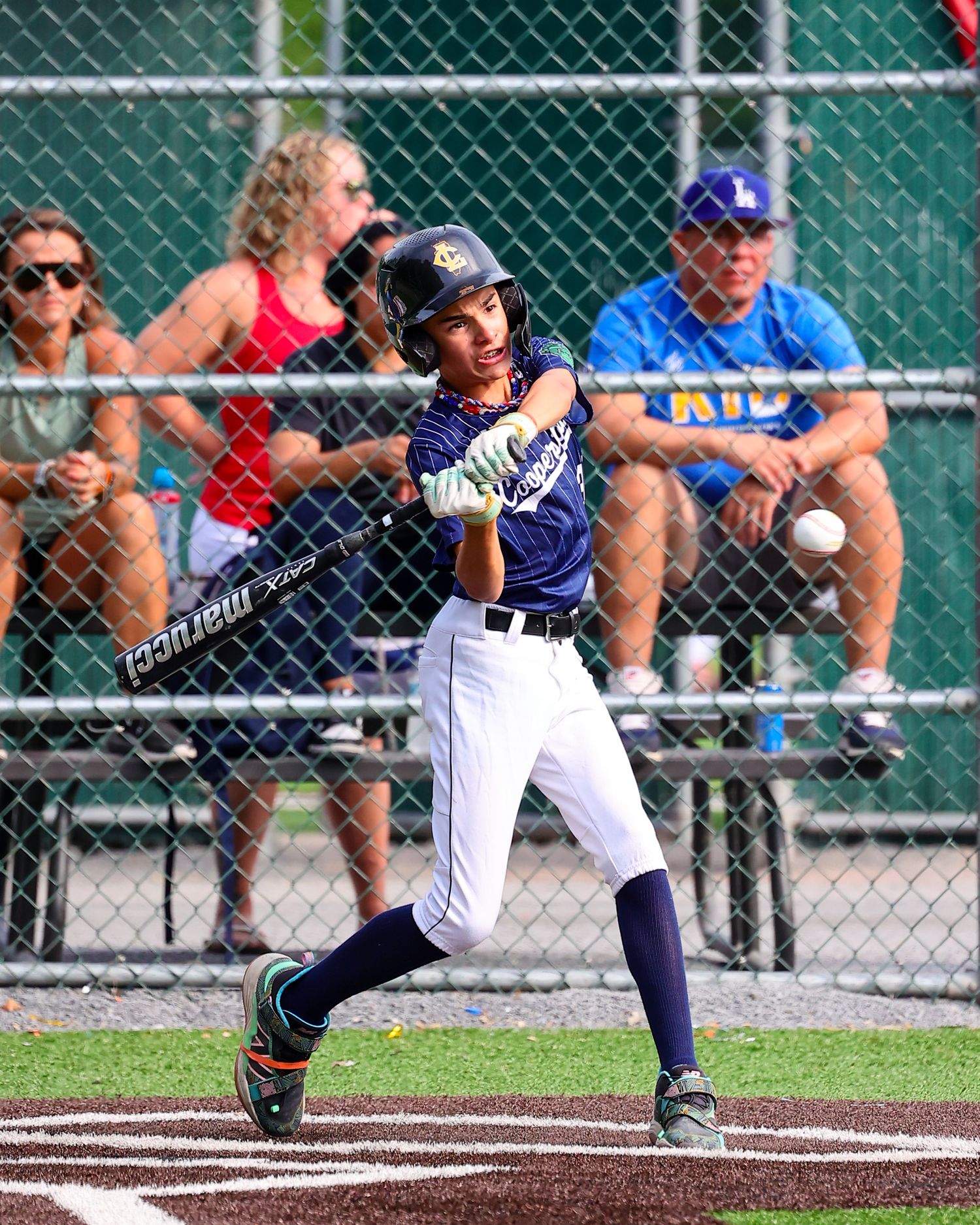 Baseball player in blue uniform slides into home plate during an intense game play moment.