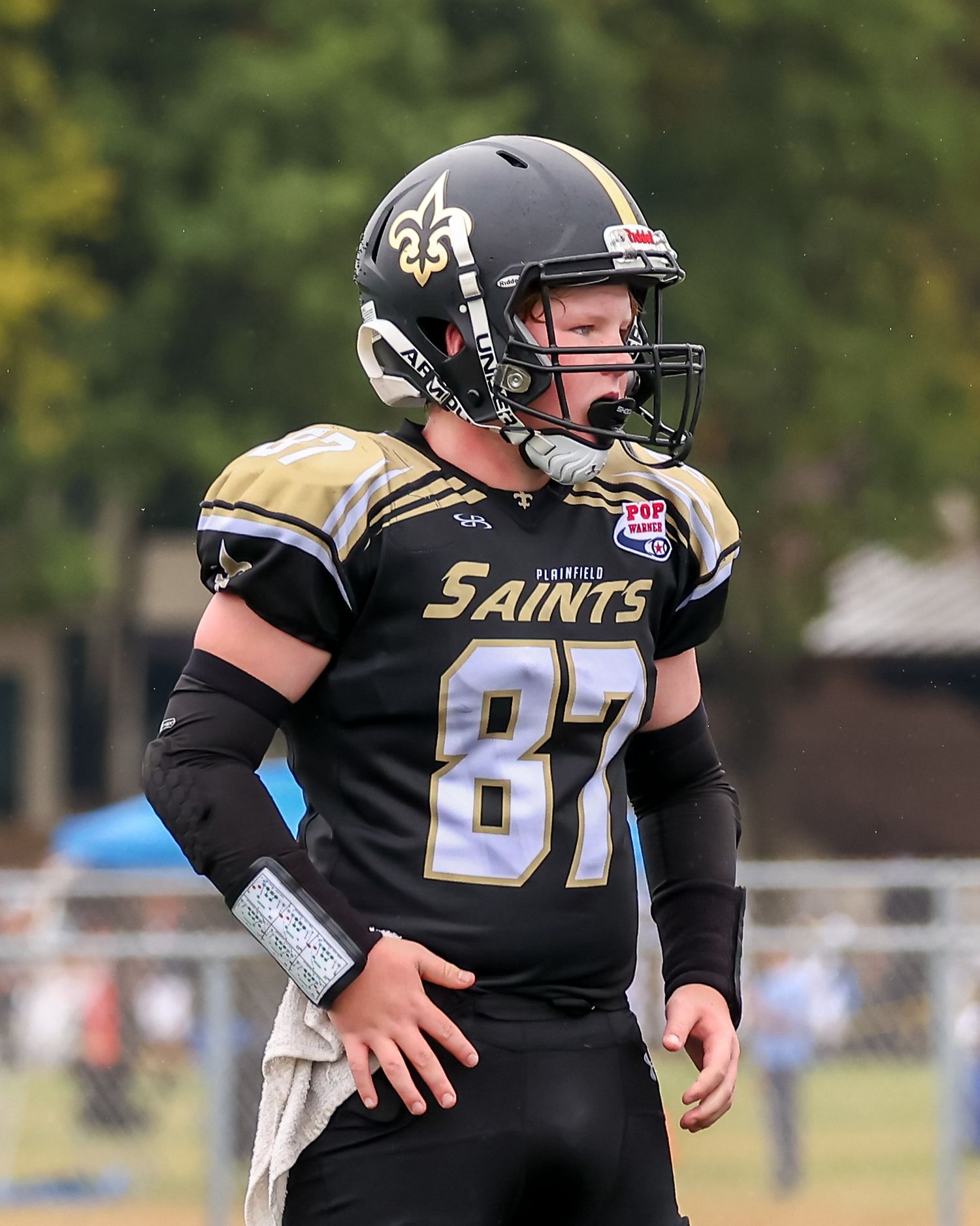 Football player in black Saints uniform number 87 stands on field during game.
