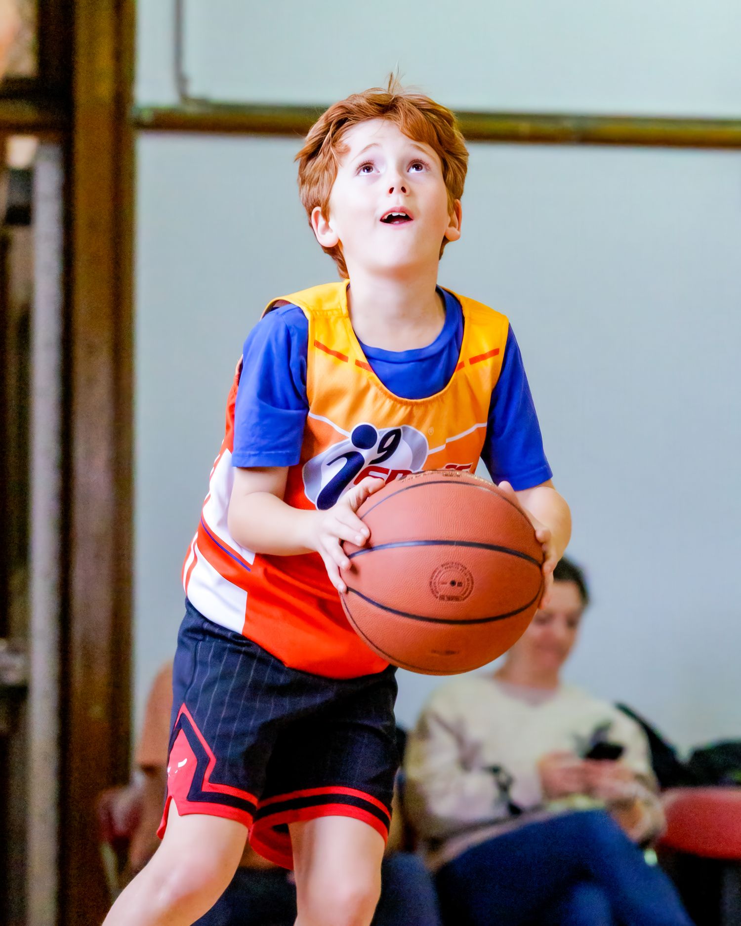 Young basketball players in bright orange jerseys practicing dribbling and ball control drills.