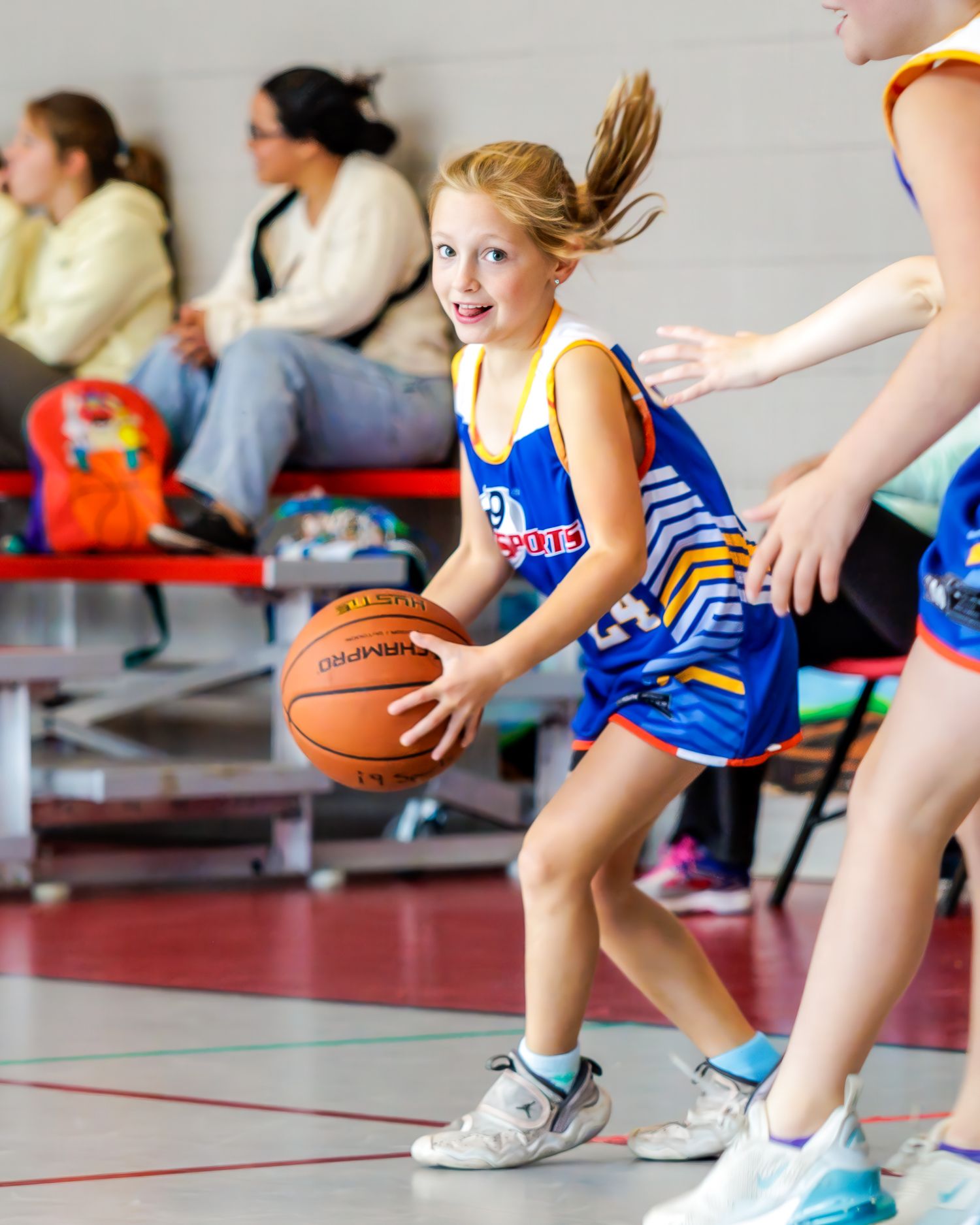 Young basketball player in blue uniform dribbles with dynamic movement during indoor game practice session.
