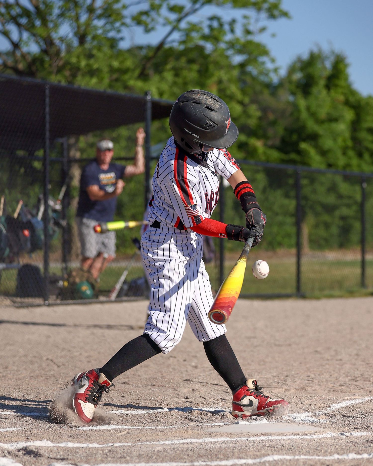 A baseball batter in striped uniform swinging at a pitch near home plate.