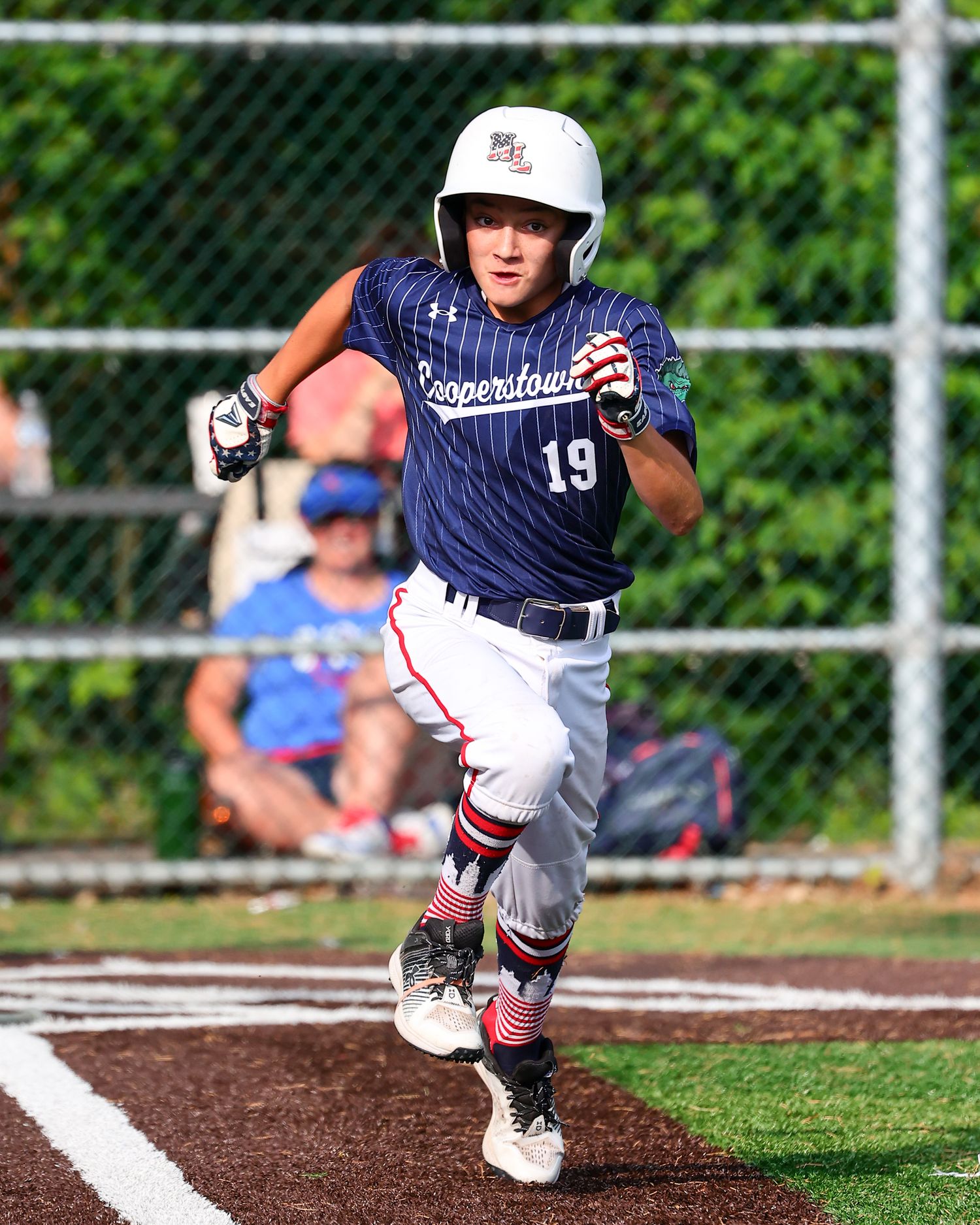 Baseball player in navy uniform slides into base during competitive game on dirt infield.
