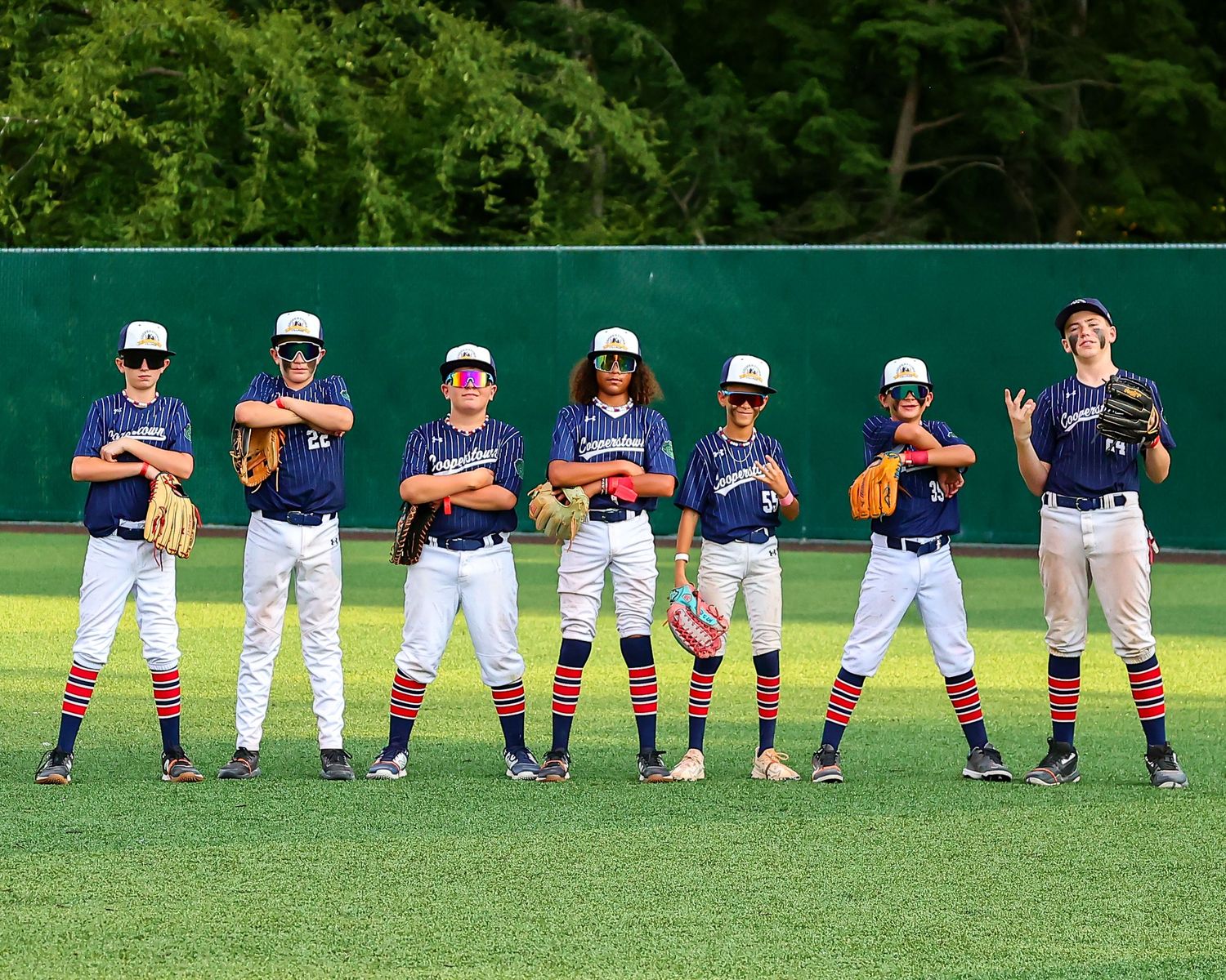 Baseball players stand  in a row on the grass field posing for camera.