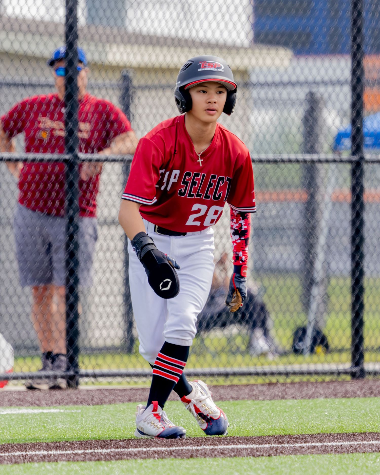 Baseball player in red and white uniform crouches in fielding position on baseball diamond.