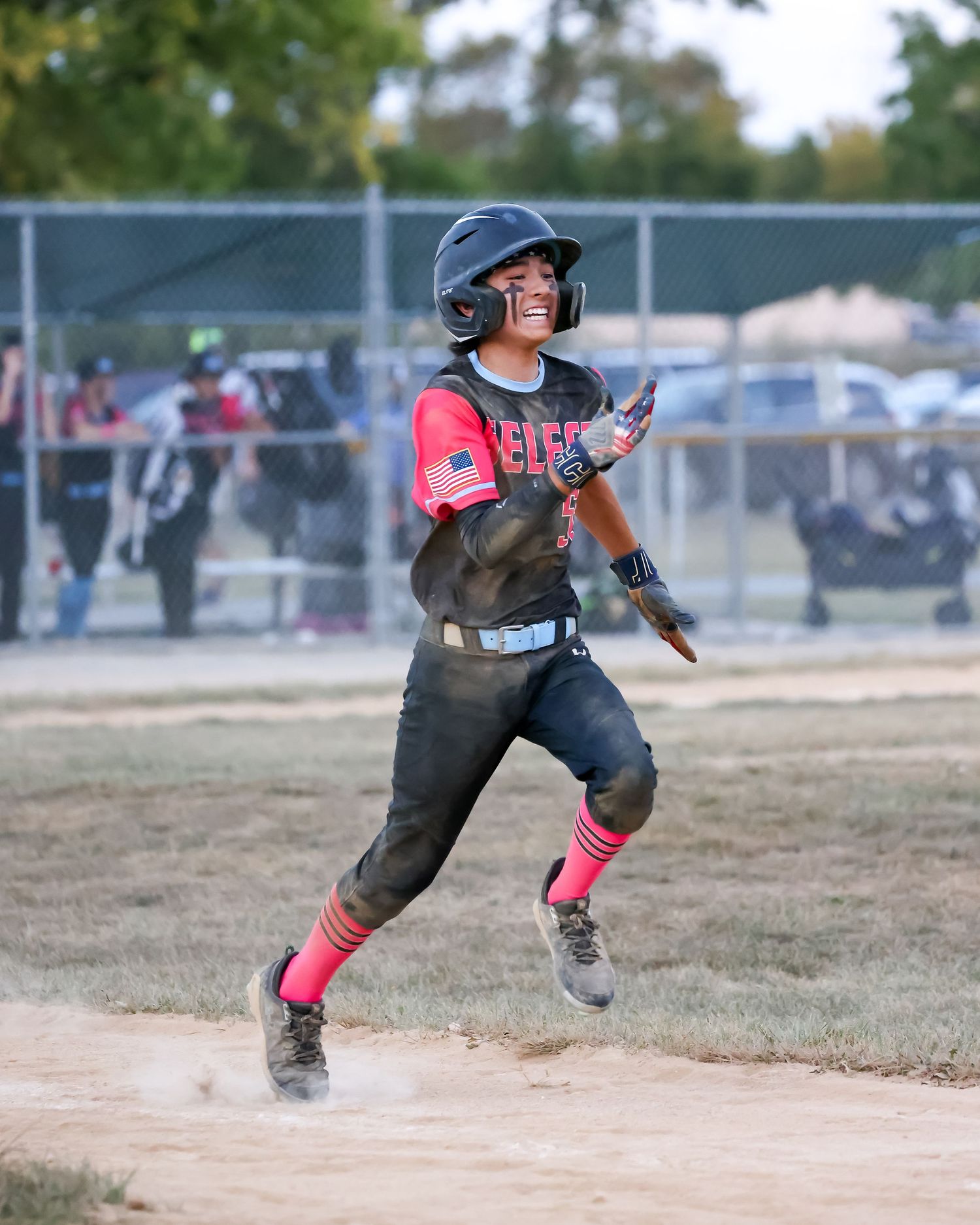 Baseball player in black and pink uniform runs bases with determination during game.